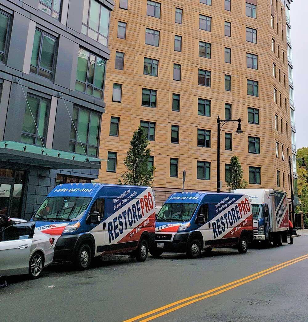 RestorePro emergency response fleet of branded vans and trucks on a Boston street